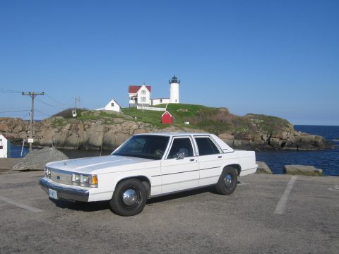 1991 Ford LTD Crown Victoria - A white 1991 Ford Crown Victoria LTD is parked near a scenic coastal lighthouse.