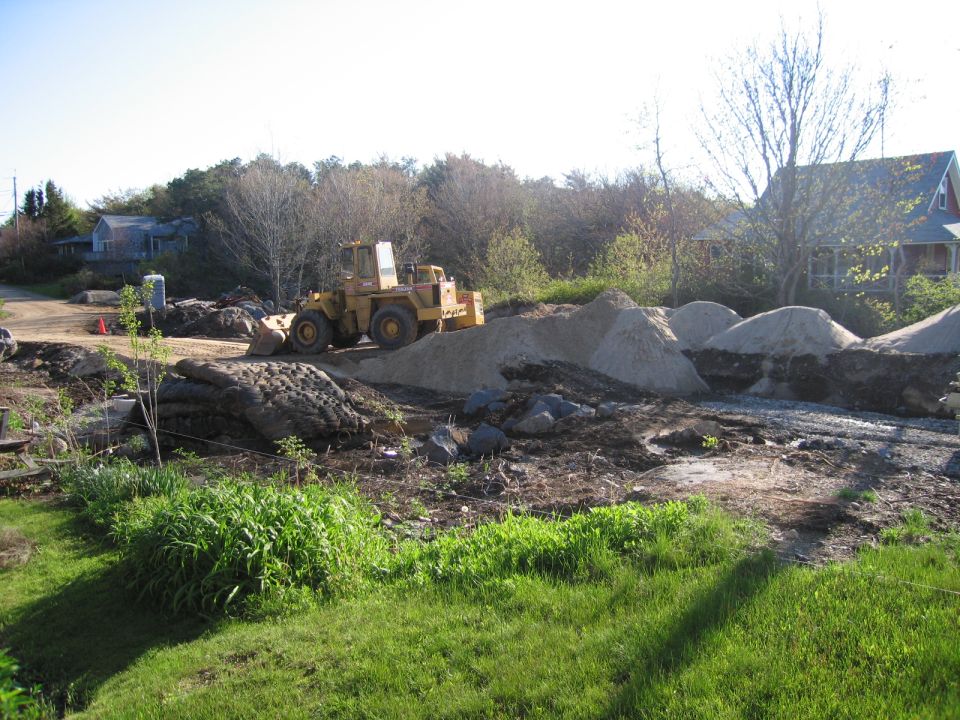 Yellow wheel loader parked on a construction site with piles of sand and dirt