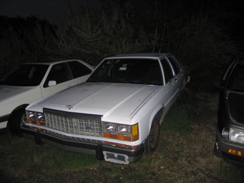 1991 Ford LTD Crown Victoria - White sedan with a prominent grille parked outdoors at night.