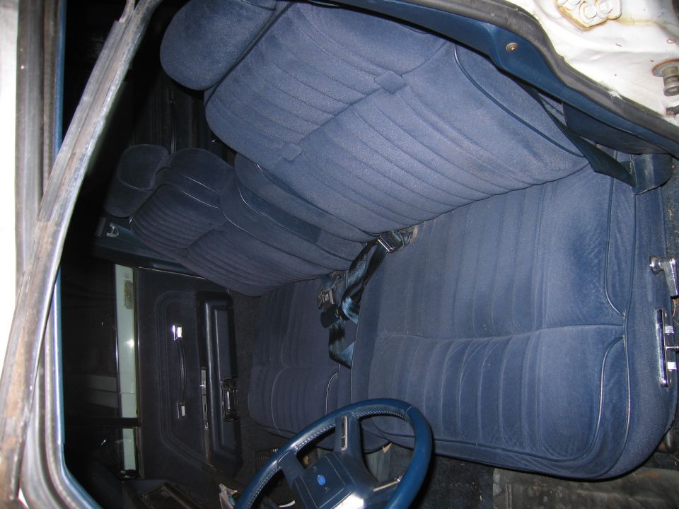 Interior view of a car showing front and rear blue velour bench seats and a blue steering wheel