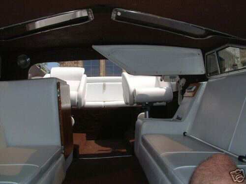 White vinyl seating and wood trim inside a boat cockpit under a dark canopy