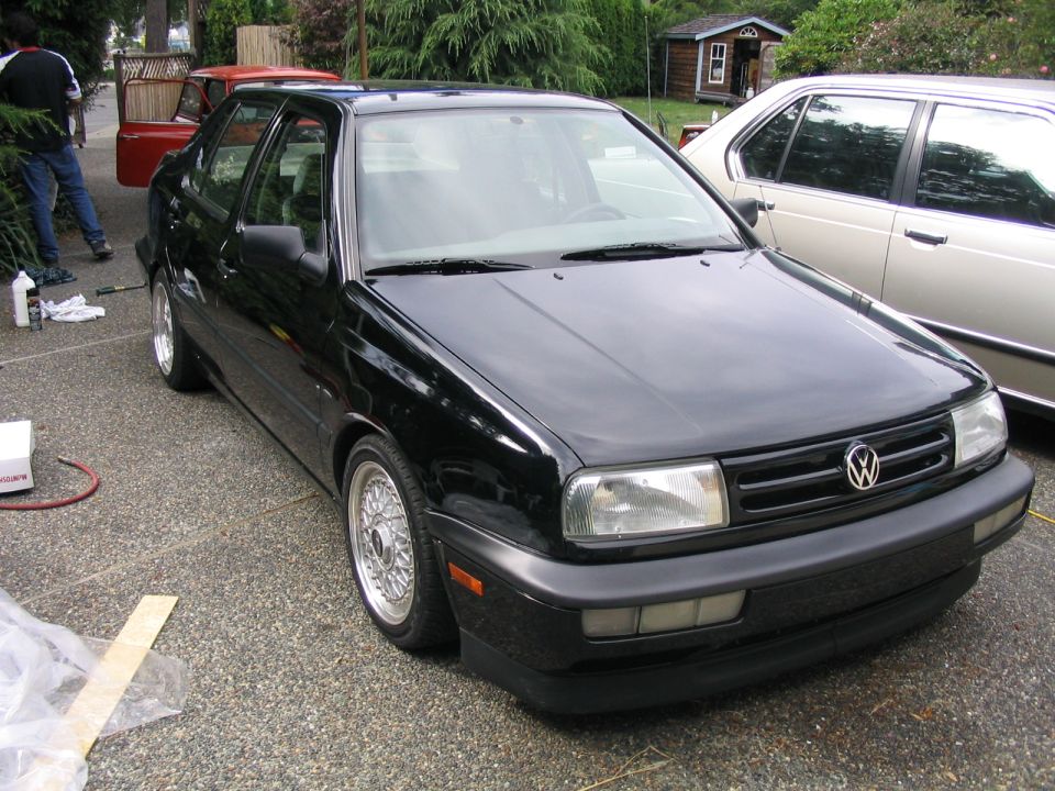 Black VW Jetta sedan lowered on chrome mesh wheels in driveway