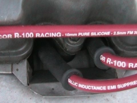 1989 Mazda MX-6 - Close-up of red R-100 Racing spark plug wires with visible text.