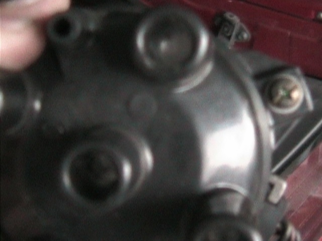 Close-up of a black distributor cap with three circular indentations