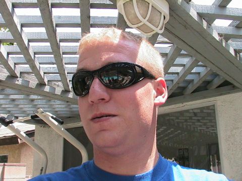 1993 Ford Taurus - A man wearing sunglasses stands outside under a wooden pergola on a sunny day.