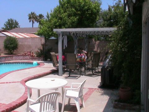 1993 Ford Taurus - A backyard scene features a swimming pool, patio furniture, and people gathered under a pergola.