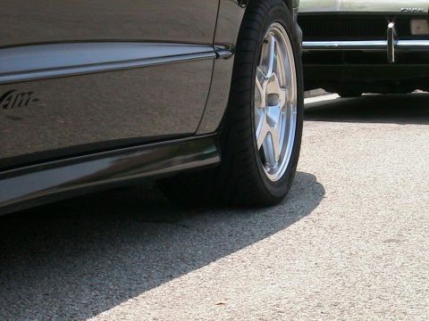 1993 Ford Taurus - Detail shot of a car's side panel and wheel, with another car visible in the background.