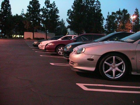 1993 Ford Taurus - Multiple vehicles are parked in a lot as the sky darkens.