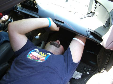 1998 Ford Taurus - A mechanic works on the interior of a vehicle, with a close-up on his hands and the dashboard components.