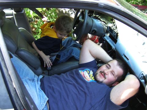1998 Ford Taurus - A man and a child relax inside the interior of a vehicle, with a Supermotors watermark visible.