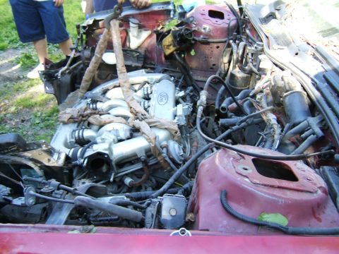 1998 Ford Taurus - The engine bay is exposed, with the engine being lifted out by chains and straps.