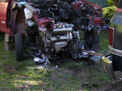 1998 Ford Taurus - Car front end is severely damaged and being towed by a pickup truck.