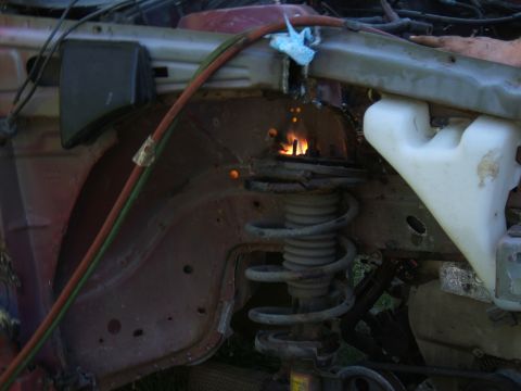1998 Ford Taurus - A car's suspension strut is being cut with a torch, with sparks flying from the metal.