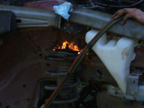 1998 Ford Taurus - Car engine bay is on fire, with flames erupting from the engine compartment.