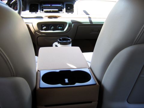 2000 Ford Crown Victoria - Interior view of a car's console, dashboard, and front seats, with a travel mug in the cup holder.