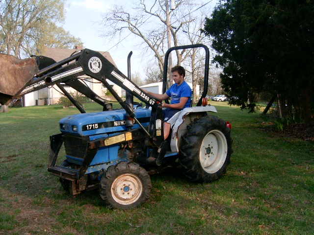 New Holland 1715 tractor with front loader, driven by a young man