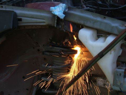1998 Ford Taurus - Metal is being cut with a torch, creating a shower of sparks near a car's suspension.