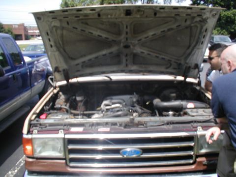1979 Ford Bronco - Engine bay of a Ford truck, with another blue truck visible to the side.