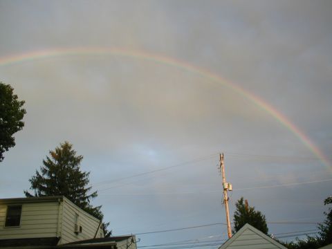 1979 Ford Bronco - A rainbow appears in the sky above houses and trees.