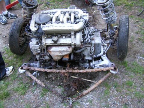 1998 Ford Taurus - The engine and front suspension assembly of a 1998 Ford Taurus SHO, partially disassembled and chained.