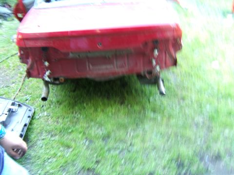 1998 Ford Taurus - The rear of a red vehicle is shown with the bumper removed, revealing the exhaust system and structural components.