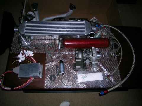1994 Ford Probe - A turbocharger kit, including an intercooler, wastegate, fuel pump, and ECU, is laid out on a table.