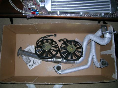 1994 Ford Probe - Automotive parts, including fans and exhaust components, are arranged inside a cardboard box.