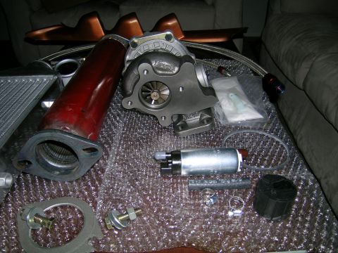 1994 Ford Probe - Various automotive performance parts, including a turbocharger, intercooler, and fuel pump, are displayed on a bubble-wrapped surface.