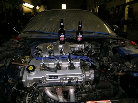 1994 Ford Probe - Car engine bay with two beer bottles placed on top of the engine cover.