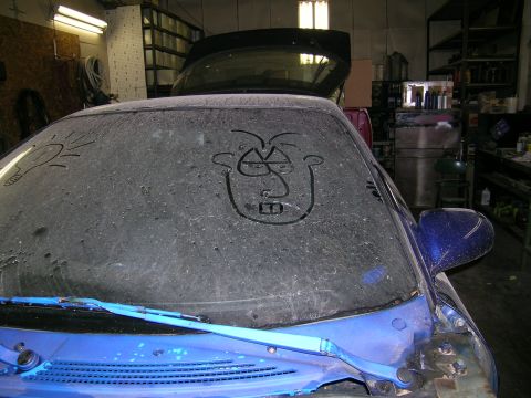1994 Ford Probe - A dusty windshield features a crudely drawn face and a lightbulb, obscuring the vehicle's details.