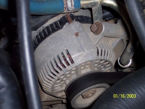 1993 Ford Bronco - This is a close-up view of a vehicle's alternator, showing the belt and surrounding engine components.