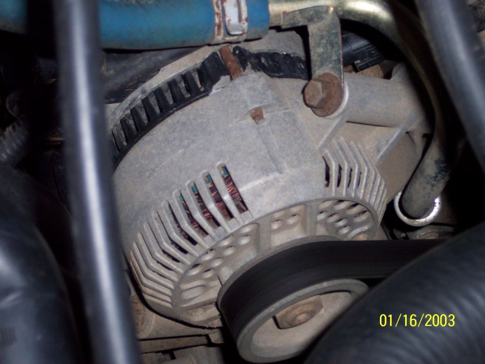 Close-up of a vehicle's alternator with a belt. Date stamp says 01/16/2003