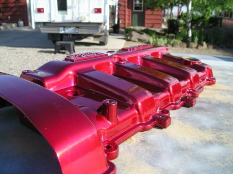 1994 Ford Probe - A freshly painted red intake manifold rests on a concrete surface with a white truck in the background.