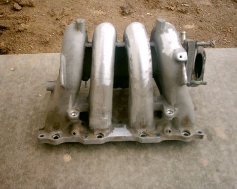 1994 Ford Probe - An intake manifold, likely from a car engine, is shown from a frontal perspective on a textured surface.