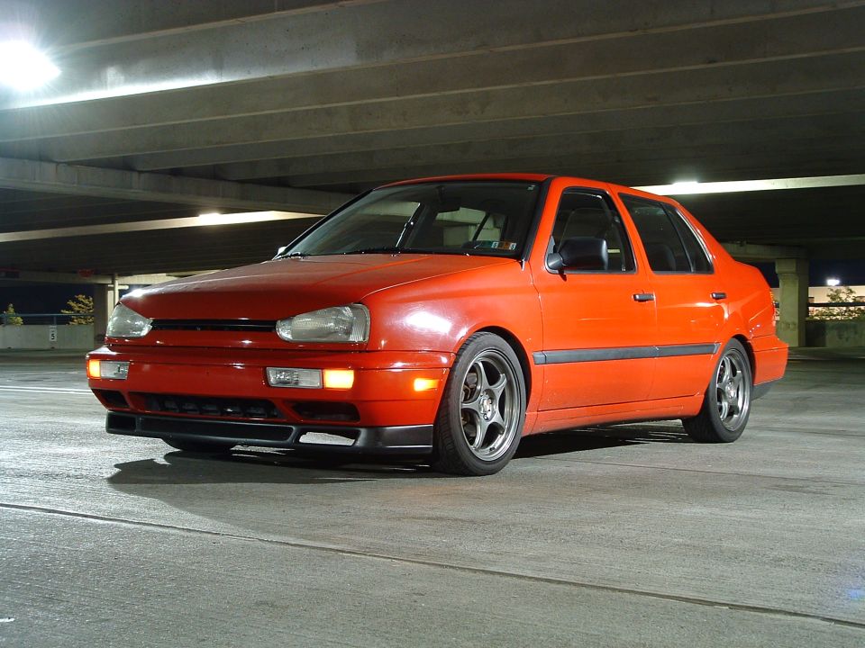 1994 Volkswagen Jetta sedan, orange, parked in a concrete garage