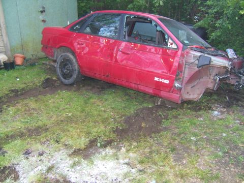 1998 Ford Taurus - This red 1998 Ford Taurus sedan shows significant front-end damage and broken windows, indicating it has been in a severe accident or is be…