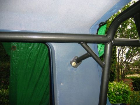 1985 Ford Bronco - Custom roll cage installed inside a vehicle, partially obscured by a green tarp. The Supermotors logo is visible in the lower right corner.