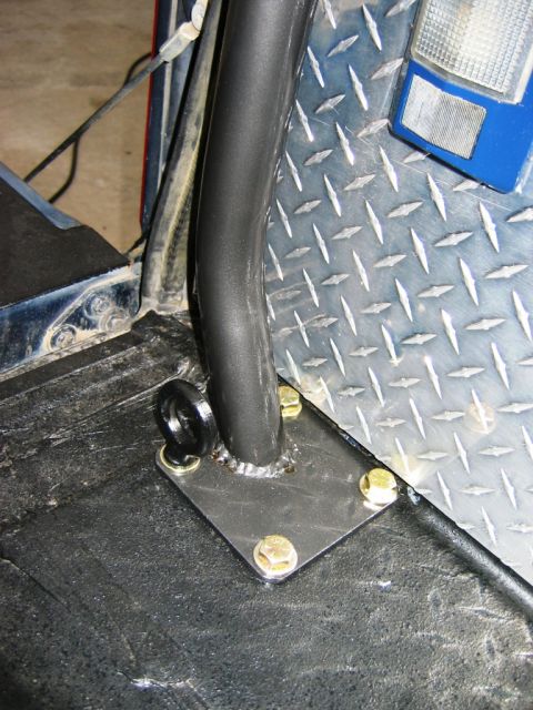 1985 Ford Bronco - Close-up of a roll cage mounting bracket and tie-down loop attached to a vehicle's interior floor.
