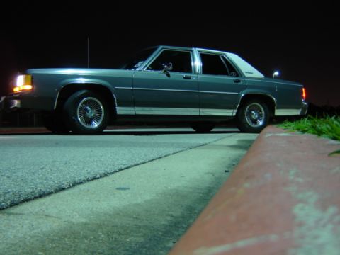 1988 Ford Crown Victoria LTD - This 1988 Ford Crown Victoria LTD is seen from the side, parked on the road at night.