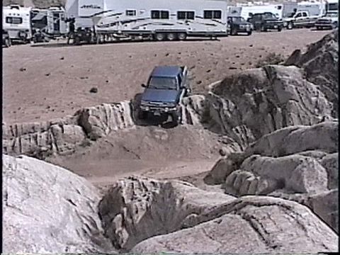 1997 Chevrolet C/K Pickup - A blue SUV is seen driving through a challenging rocky landscape.