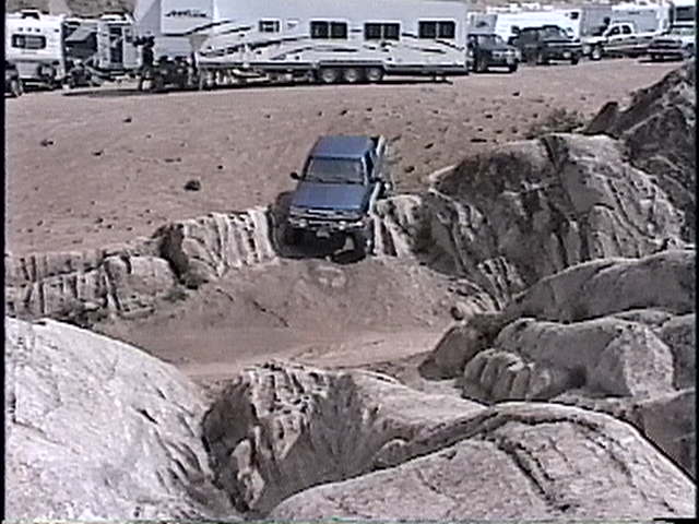 Blue SUV navigating a rocky off-road course with large boulders