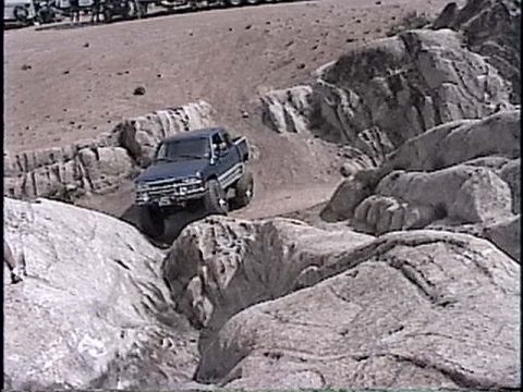 1997 Chevrolet C/K Pickup - A blue 1997 Chevrolet C/K Pickup navigates a challenging rocky trail, demonstrating its off-road capability.