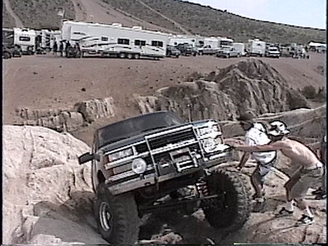 1997 Chevrolet C/K Pickup truck navigating rocky terrain with a person pushing