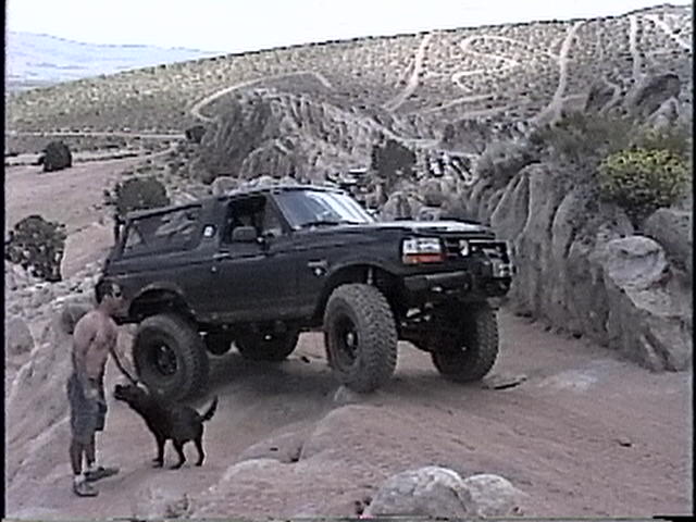 1997 Ford Bronco on a rocky trail with a man and dog