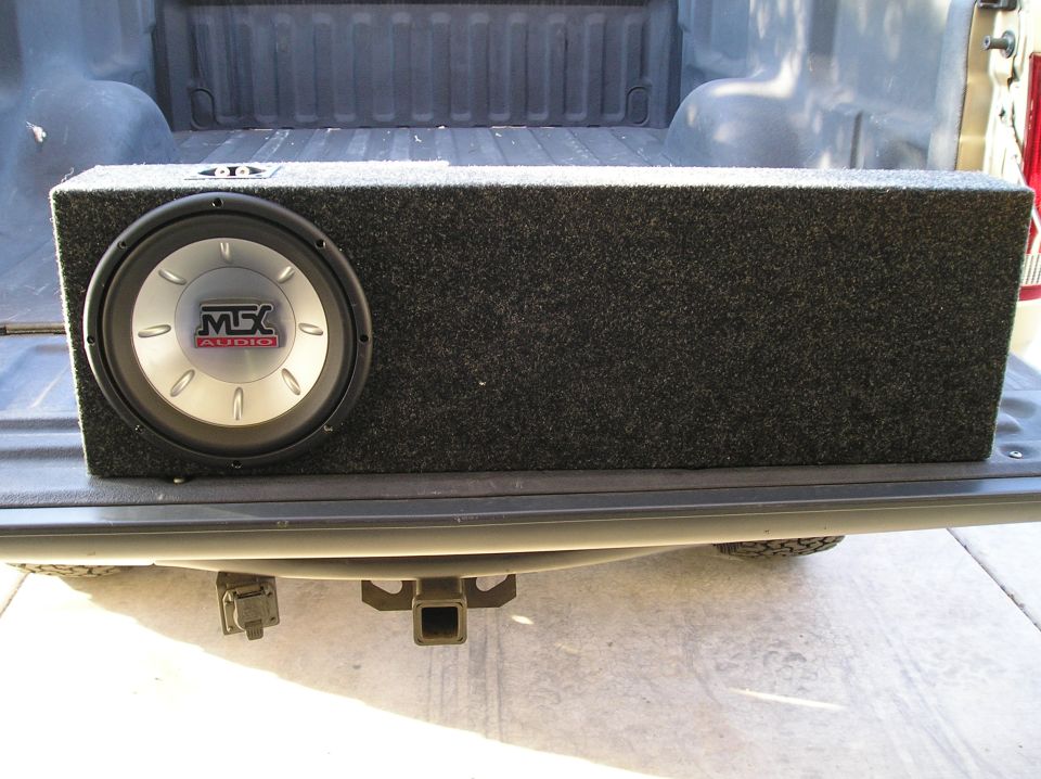 Carpeted MTX Audio subwoofer box on the open tailgate of a pickup truck bed