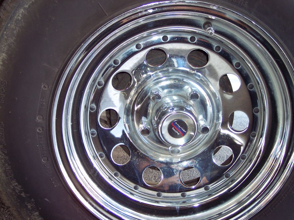 Chrome wheel with tire, center cap reads 'American Racing'