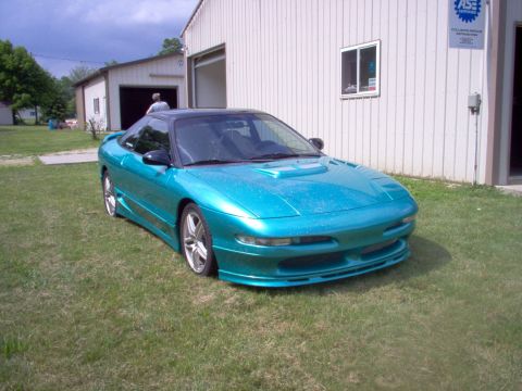 1993 Ford Probe - This teal coupe features a custom body kit and a black roof, parked outside a building.
