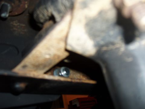 1994 Ford Bronco - Close-up view of a rusty metal bracket and bolt, likely part of a vehicle's undercarriage.
