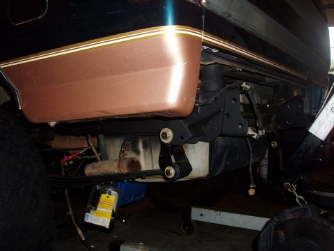 1994 Ford Bronco - The rear suspension and fuel tank area of a vehicle are visible, with a two-tone paint scheme on the body panel.