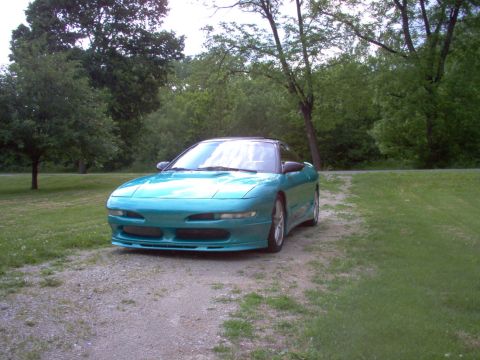 1993 Ford Probe - A teal 1993 Ford Probe is parked on a gravel driveway with trees in the background.